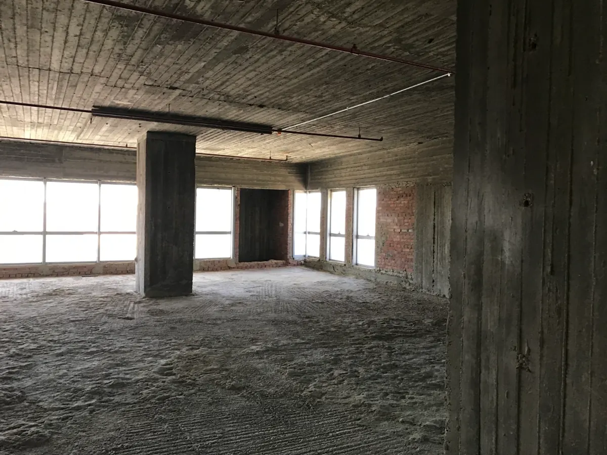 Leeres Bürogeschoss im Rohbau mit Stützen und Fensterband
